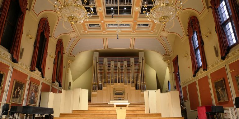 The interior of the Royal Academy of Music, featuring a grand organ and ornate ceiling.